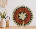Decorative woven wall hanging with geometric pattern on a wooden surface.
